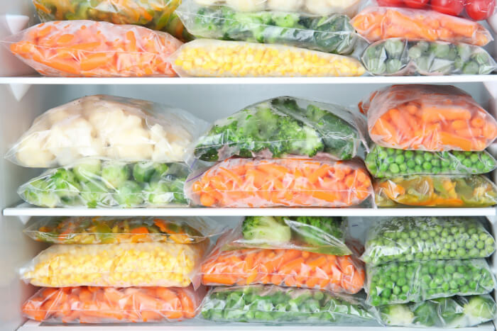 Congelador cheio de alimentos congelados corretamente, em embalagens plásticas próprias para o uso.