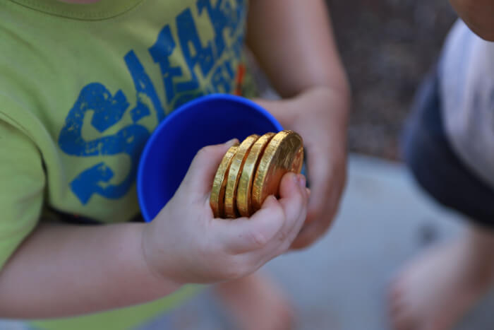 Criança segurando moedas de chocolate: o prêmio da caça ao tesouro.