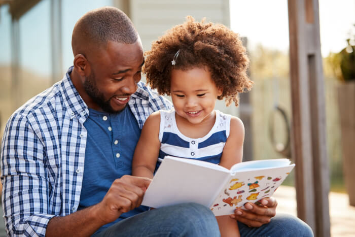 Pai lendo um livro para sua filha pequena