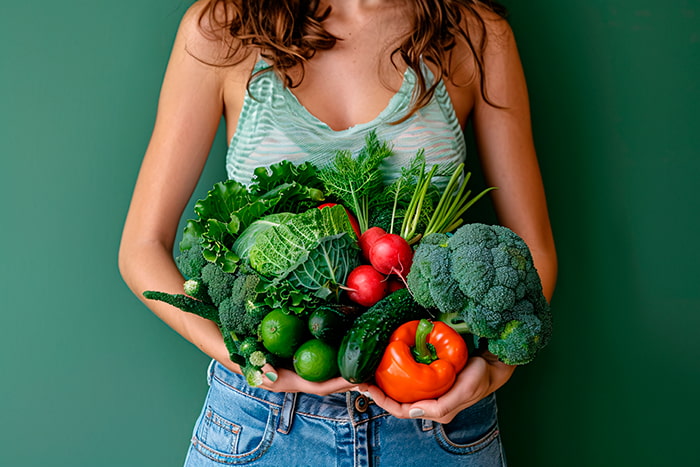 mulher segurando vários alimentos ricos em fibras
