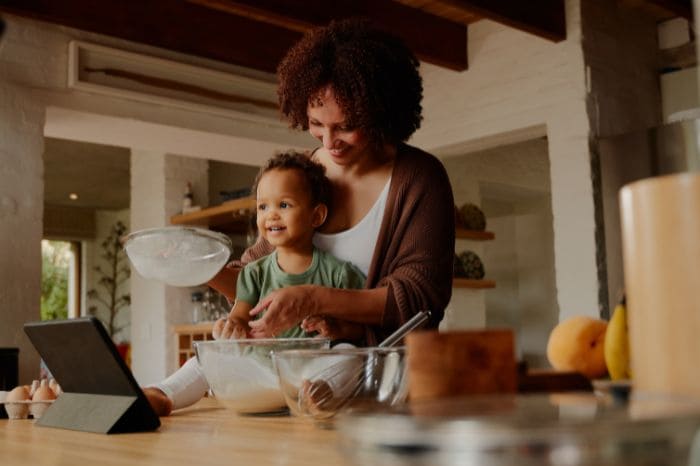 Mãe cozinhando com filho pequeno.